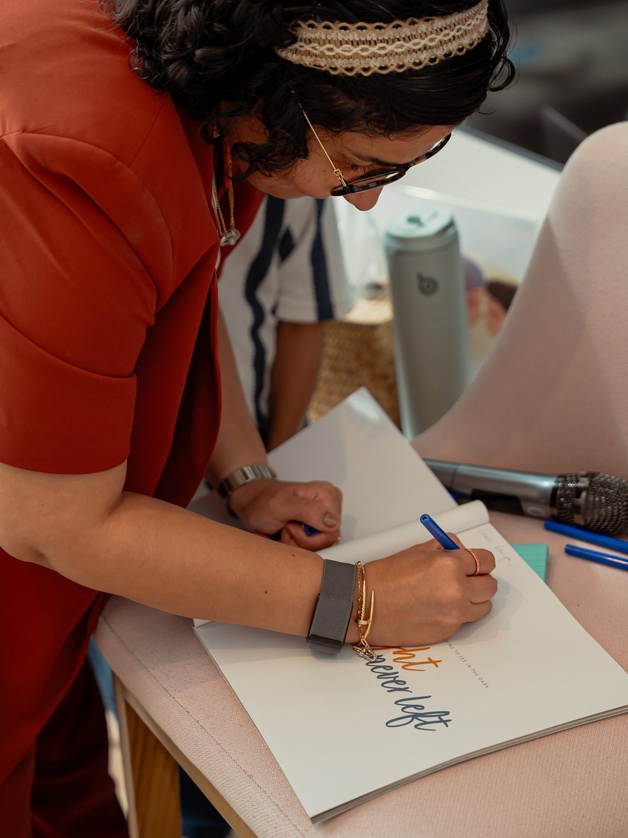 Rucha signing a copy of The Light Never Left